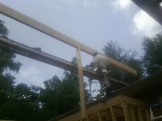 Carpenter setting a ridge beam over a new addition frame — Ice Dam Removal by Roofing Brothers in Laconia