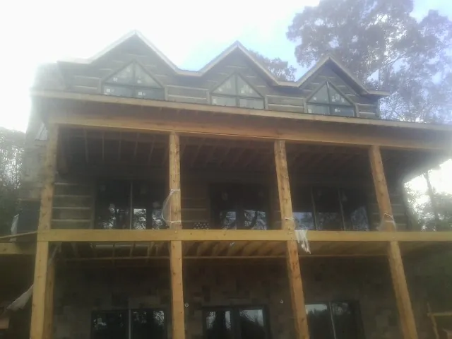 Dormers and porch framing on a large log home under construction — Roof Coating work by our crew in Laconia