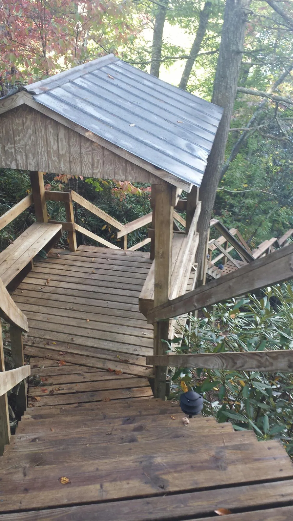 Metal roofed shelter over wooden steps on a wooded walkway — Skylight Repair & Installation work by our crew in Laconia