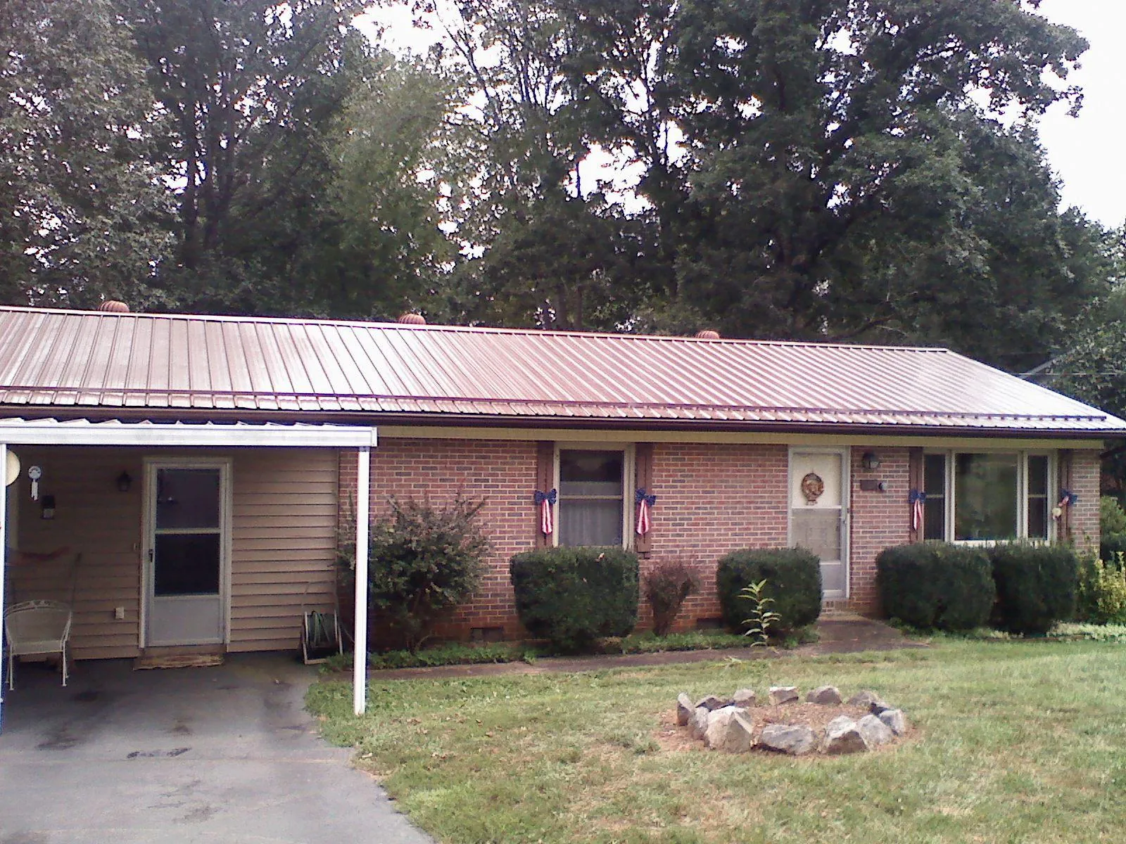 Bronze metal roof and carport on a brick ranch home — Roof Repair work by our crew in Laconia