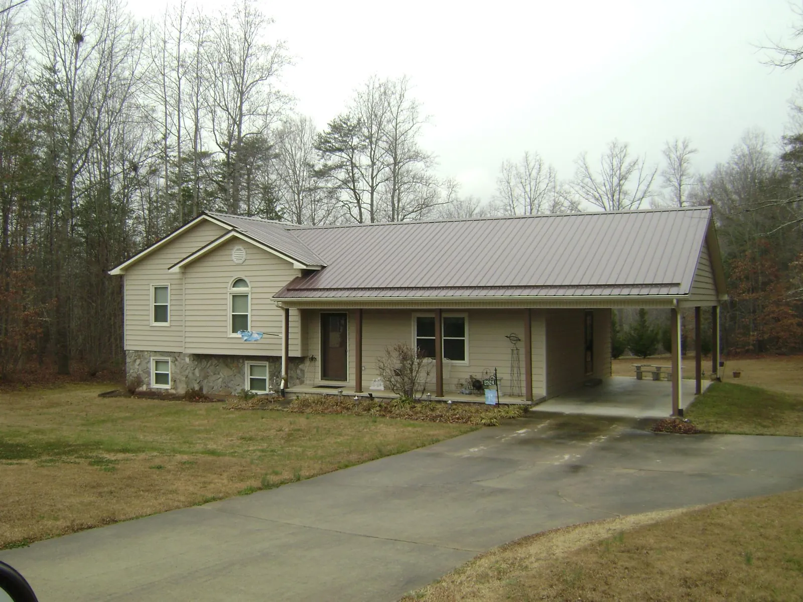 Brown metal roof on a tan split level home with an attached carport in Laconia