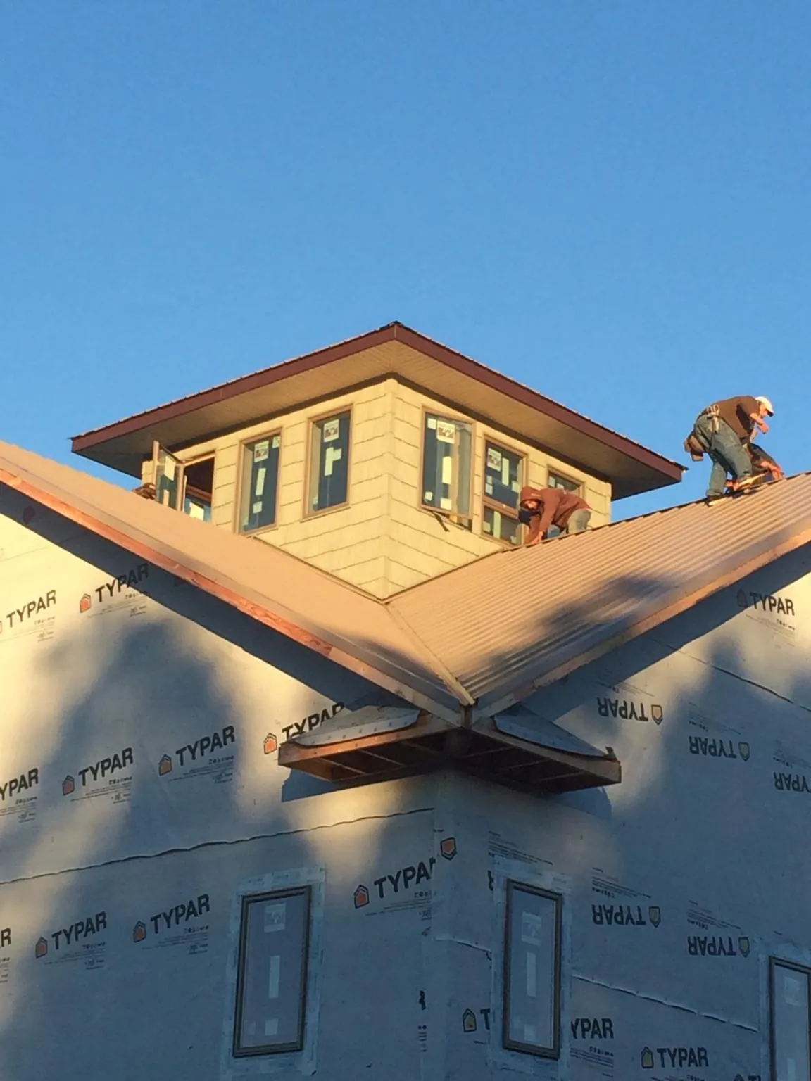Roofers working around a rooftop cupola on a new metal roof at sunset — Roof Waterproofing in Laconia by Roofing Brothers
